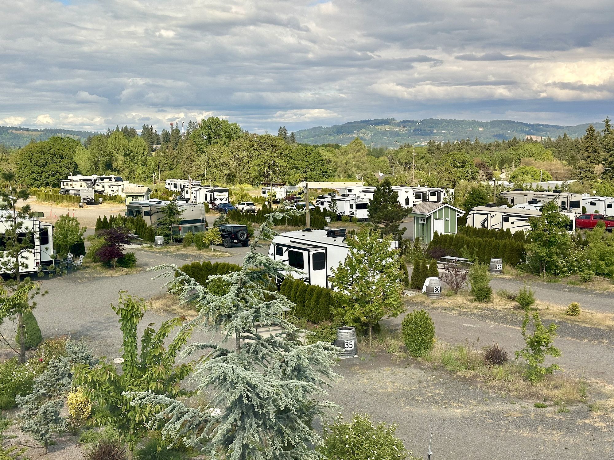 The image shows a campground or RV park with multiple RV trailers surrounded by trees and natural scenery in Dundee, OR.